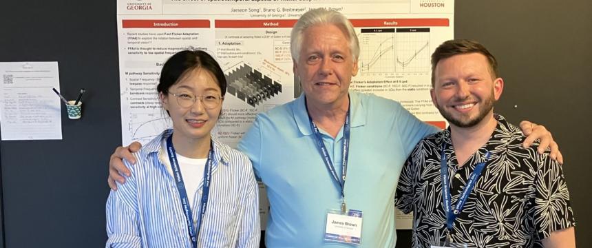 Dr. Brown standing between his students, Jaeseon Song and Ralph Hale, in front of their poster presentation, titled "the effect of spatiotemporal aspects of flicker adaptation on contrast discrimination," at an academic conference