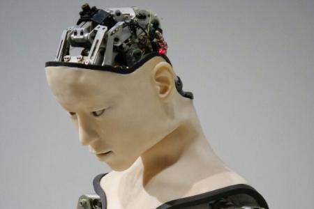 humanoid robot with a downturned, lifelike face and an exposed cranium, displaying its inner mechanics