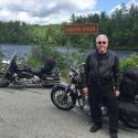 Dr. Brown standing beside his motorcycle in front of the Hudson River in the Adirondack Mountains